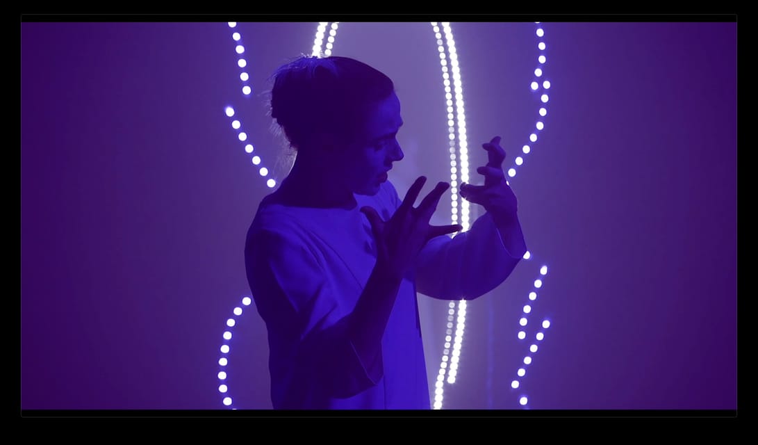 Un comédien entouré d’un cercle de lumières violettes.