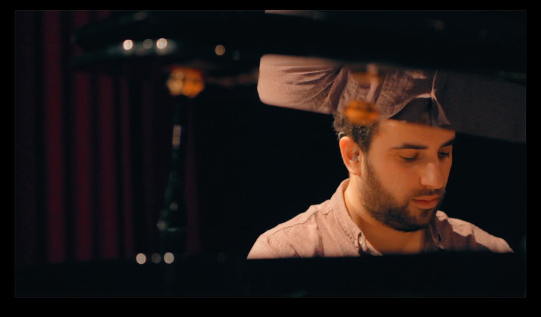 Un pianiste concentré dans la pénombre.