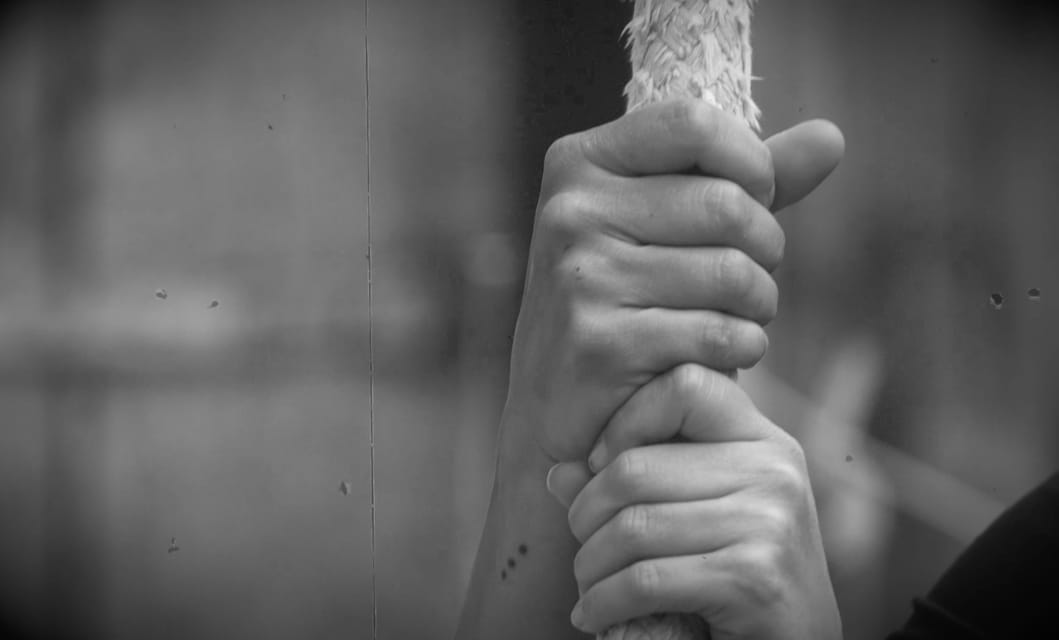 Des mains agrippées à une corde, en noir et blanc.